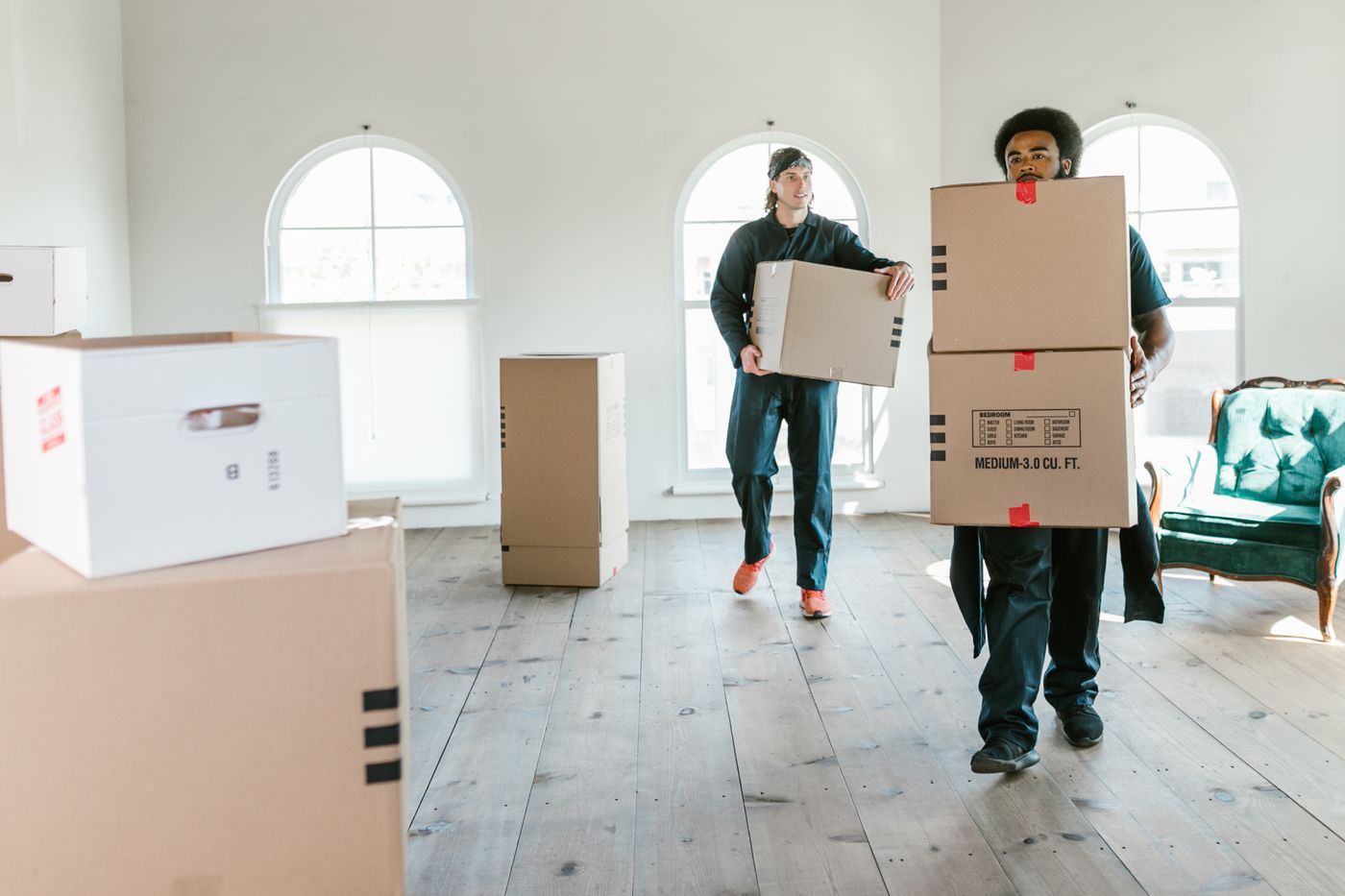 Umzugskräfte tragen Kartons in eine helle Wohnung